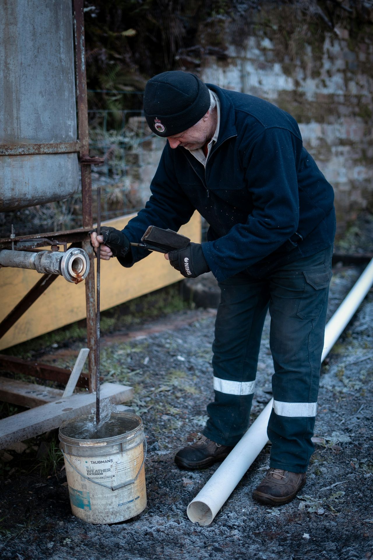 A man checks the substance in a bucket.